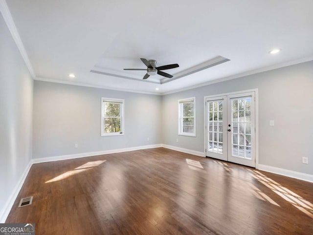 unfurnished room with baseboards, visible vents, a raised ceiling, wood finished floors, and french doors