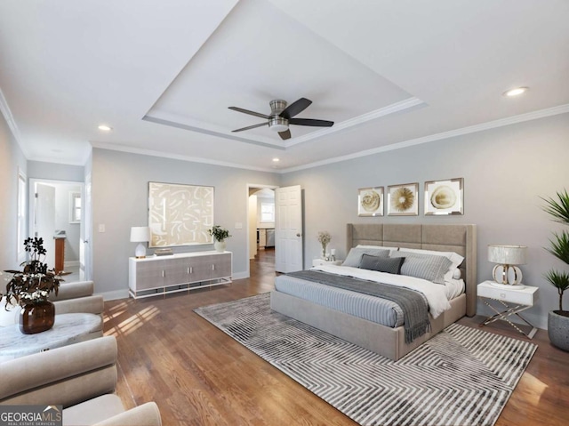 bedroom featuring crown molding, a tray ceiling, wood finished floors, and baseboards