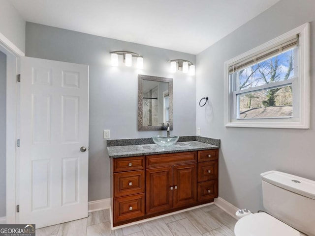 full bath featuring toilet, baseboards, a shower, and vanity