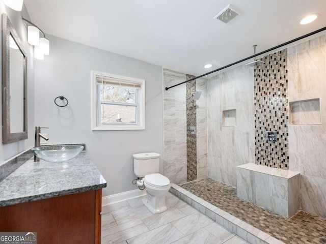 bathroom featuring toilet, tiled shower, vanity, and visible vents
