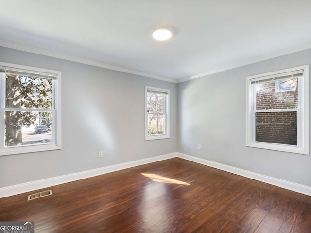 unfurnished room featuring baseboards, visible vents, dark wood finished floors, and ornamental molding