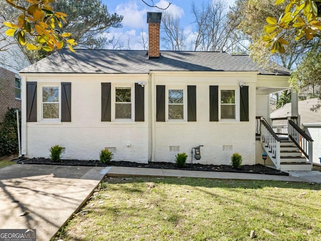 view of side of home featuring crawl space, a yard, a chimney, and brick siding