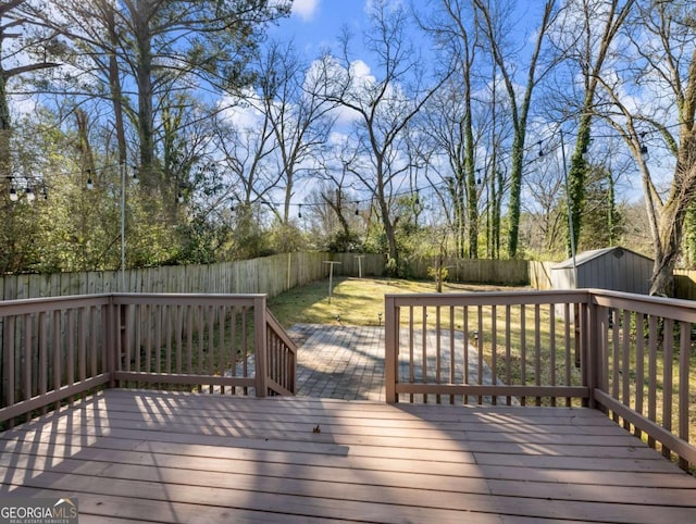 deck with a storage shed, an outdoor structure, and a fenced backyard