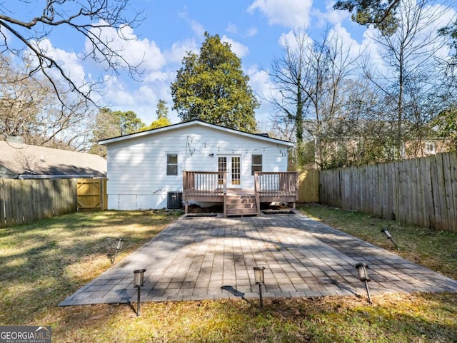 rear view of property with central AC unit, a fenced backyard, a yard, a wooden deck, and a patio area
