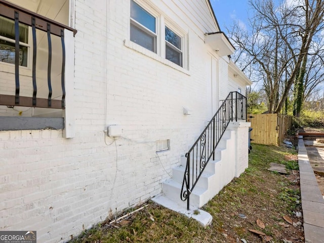 view of side of property featuring brick siding and fence