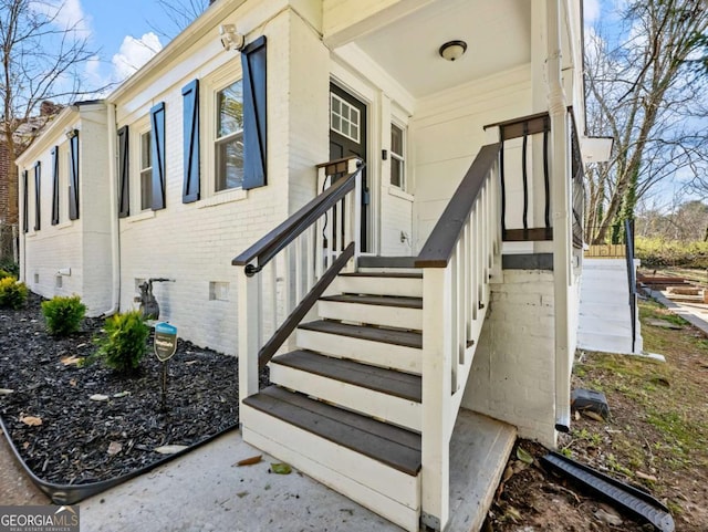 entrance to property featuring crawl space and brick siding