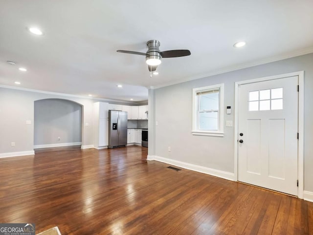 unfurnished living room with ornamental molding, dark wood finished floors, and arched walkways
