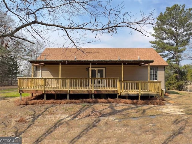 view of front of house with a deck and a shingled roof