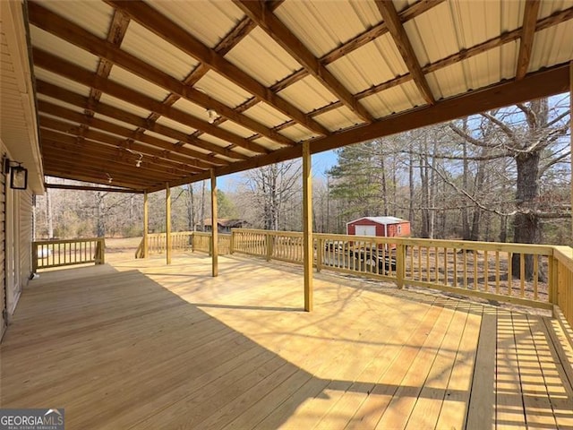 wooden terrace featuring a shed and an outbuilding