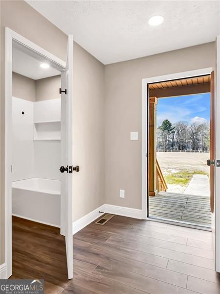 doorway to outside with wood finished floors and baseboards