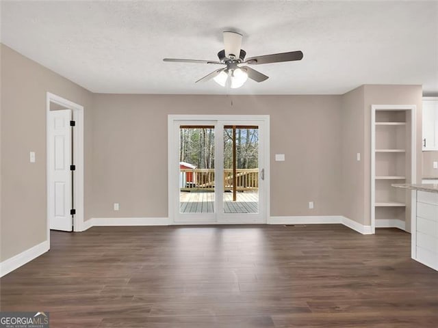 unfurnished living room with a ceiling fan, a textured ceiling, baseboards, and dark wood-type flooring