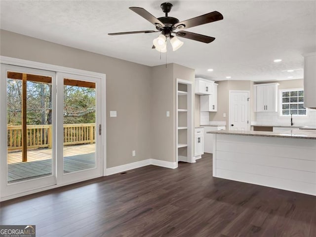 unfurnished living room with recessed lighting, dark wood-style flooring, a healthy amount of sunlight, and baseboards