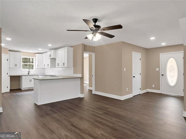 kitchen with dark wood-style floors, white cabinets, a peninsula, and decorative backsplash