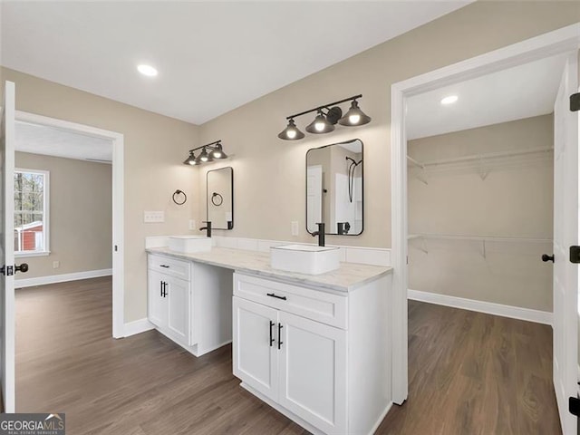 full bathroom featuring a sink, double vanity, wood finished floors, and baseboards