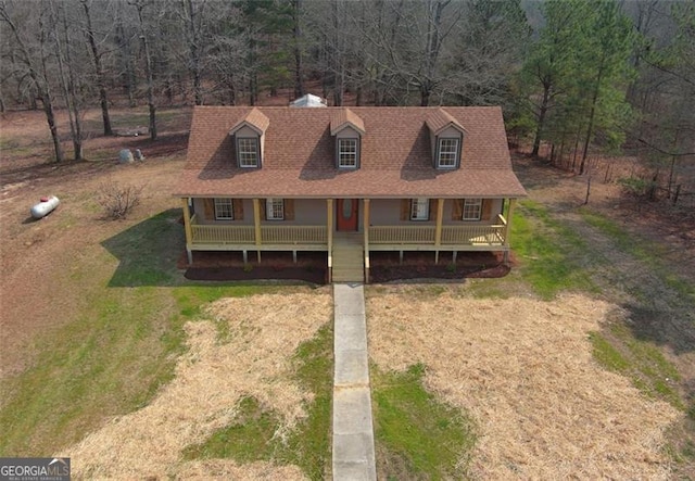 view of front of property featuring driveway, covered porch, and a front lawn