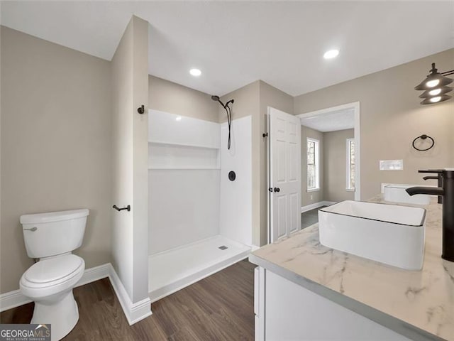 full bathroom with a shower, wood finished floors, toilet, and baseboards