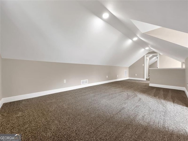 additional living space with lofted ceiling, baseboards, and dark carpet