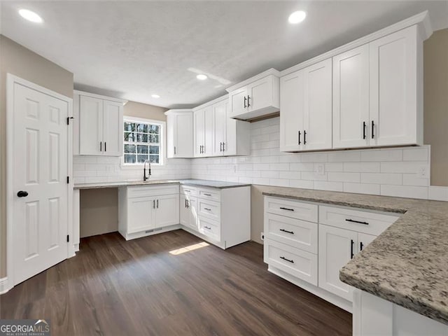 kitchen with dark wood-style flooring, a sink, and light stone countertops