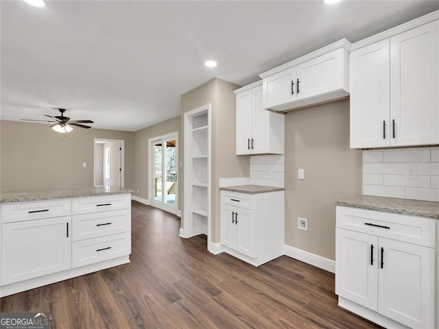 kitchen with light stone counters, dark wood-style flooring, and baseboards