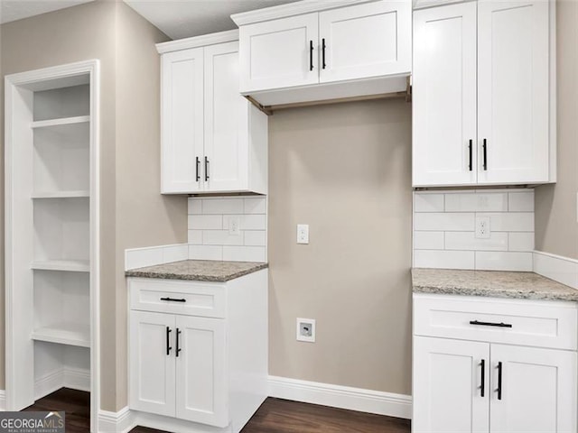 kitchen featuring light stone counters, dark wood-style flooring, white cabinets, and baseboards