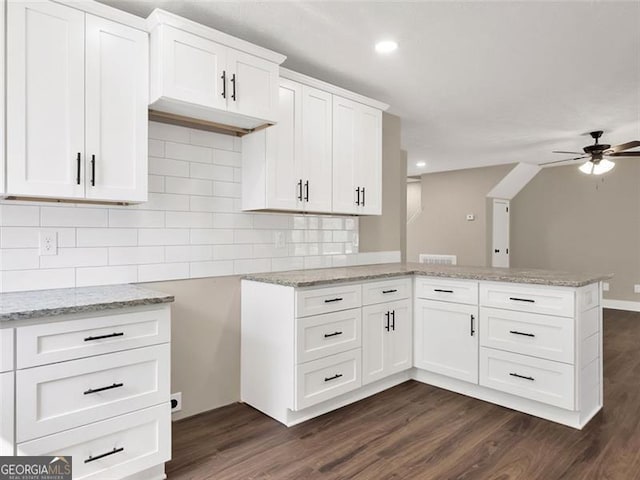 kitchen with a peninsula, backsplash, a ceiling fan, and light stone countertops