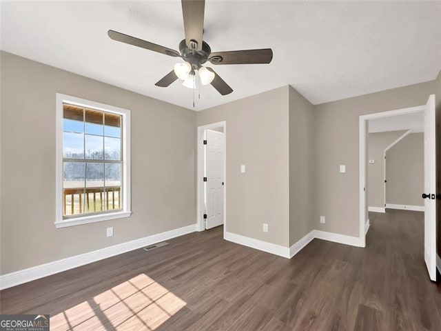 unfurnished bedroom featuring dark wood-style floors, ceiling fan, visible vents, and baseboards