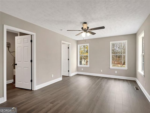 unfurnished bedroom with baseboards, a textured ceiling, visible vents, and dark wood-style flooring