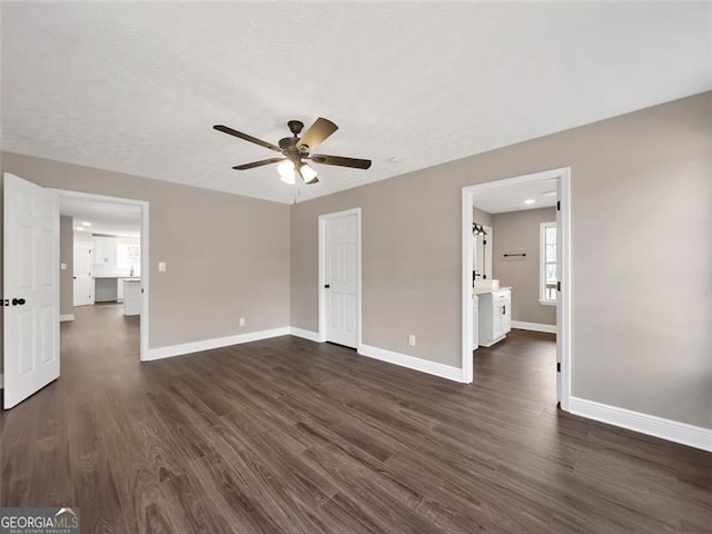 unfurnished bedroom with a ceiling fan, baseboards, and dark wood-type flooring