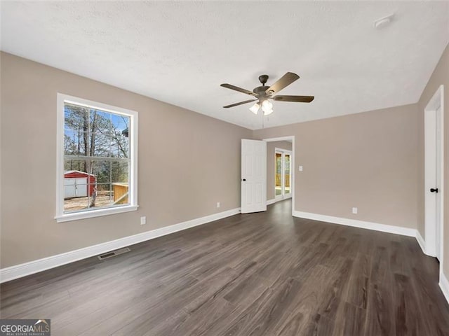 unfurnished bedroom with dark wood-style floors, visible vents, a ceiling fan, a textured ceiling, and baseboards