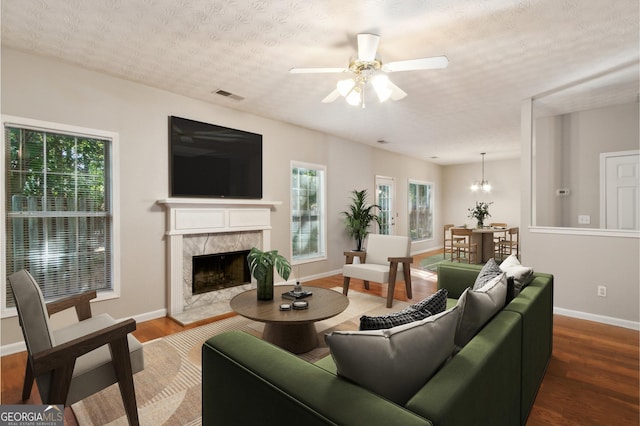 living area with plenty of natural light, wood finished floors, visible vents, and a high end fireplace