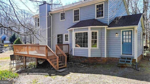 rear view of property featuring entry steps, a chimney, and a wooden deck