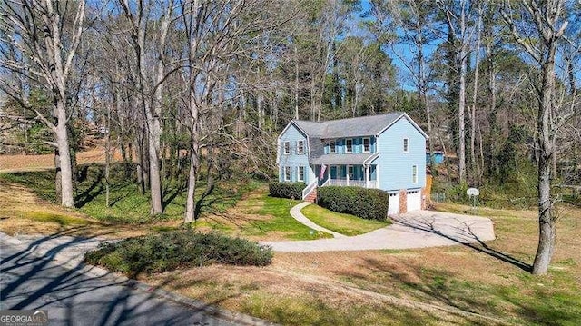 colonial-style house with a gambrel roof, an attached garage, driveway, and a front lawn