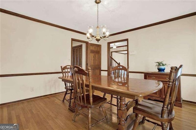 dining space featuring baseboards, ornamental molding, light wood-type flooring, and an inviting chandelier