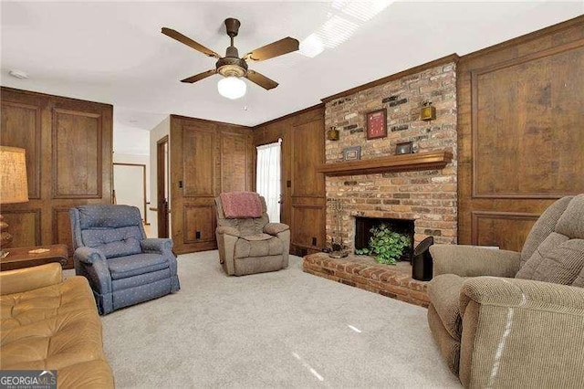 living area featuring ceiling fan, wood walls, a brick fireplace, and light colored carpet