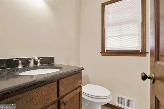 half bathroom with visible vents, vanity, and toilet