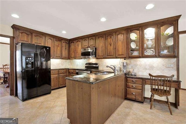 kitchen with stainless steel appliances, a peninsula, a sink, decorative backsplash, and glass insert cabinets