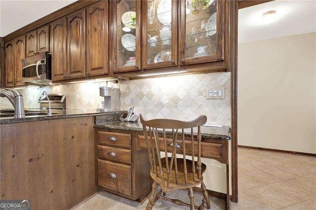 home office featuring light tile patterned floors, a sink, and baseboards