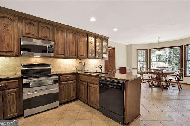 kitchen with a peninsula, appliances with stainless steel finishes, a sink, and tasteful backsplash