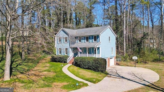 view of front facade featuring a porch, a garage, driveway, a front lawn, and stairs