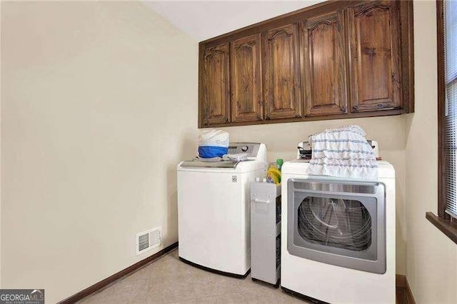 washroom featuring washing machine and dryer, cabinet space, visible vents, and baseboards