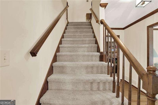 staircase with crown molding and wood finished floors