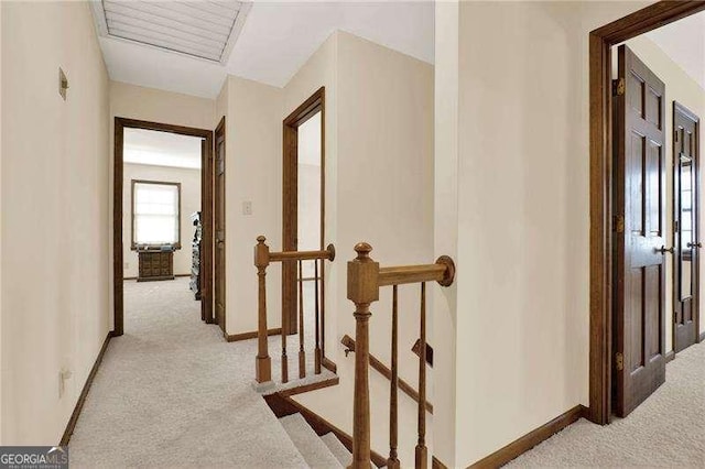 corridor with baseboards, light colored carpet, and an upstairs landing