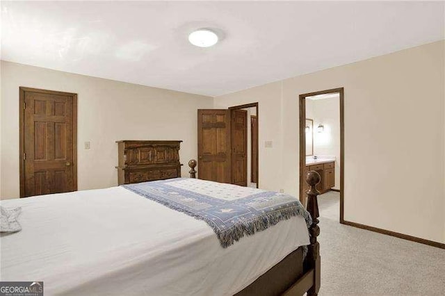 bedroom featuring light carpet, baseboards, and ensuite bathroom