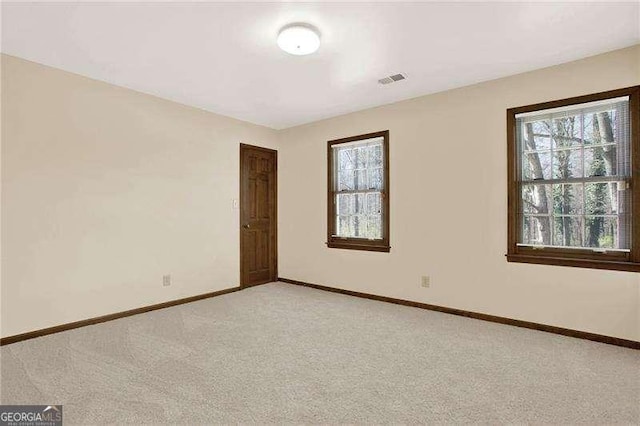 unfurnished room featuring light carpet, baseboards, and a wealth of natural light