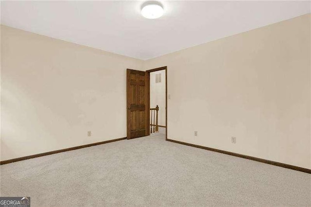 spare room featuring light colored carpet and baseboards