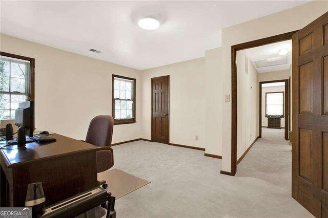 office area with baseboards, visible vents, and light colored carpet