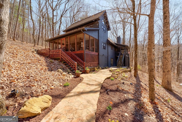 view of property exterior with stairway, a chimney, and a sunroom