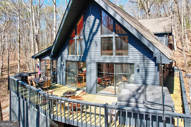 exterior space with an outdoor fire pit, a deck, and a shingled roof