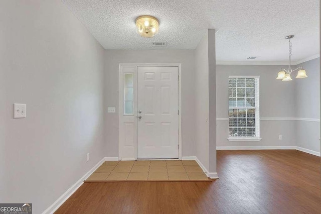 entrance foyer with baseboards, wood finished floors, visible vents, and a notable chandelier