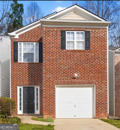 view of front of home featuring an attached garage, concrete driveway, and brick siding